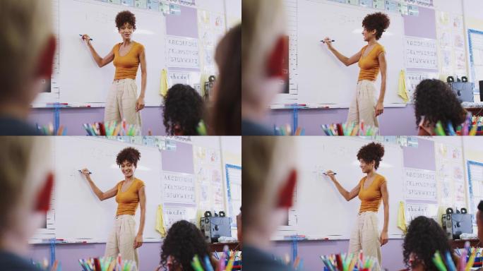 女教师站在学校教室的白板上给小学生上课