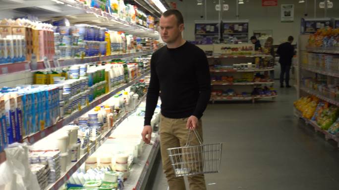 这个年轻人在超市挑选和购买牛奶。