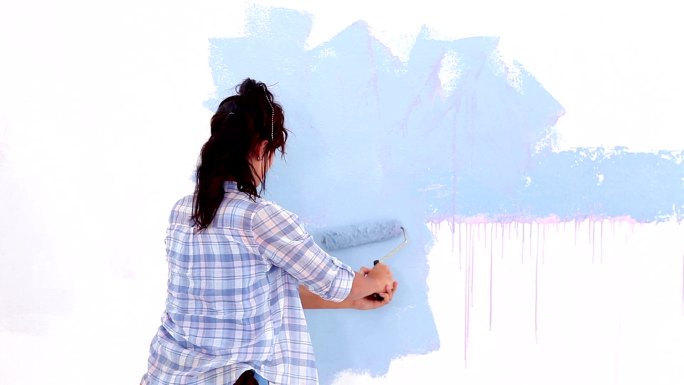 漂亮的女人在粉刷墙壁