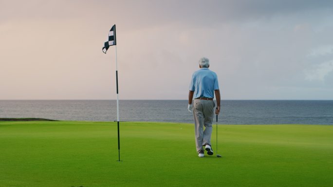 高尔夫球手漫步在绿色、奢华的球场里