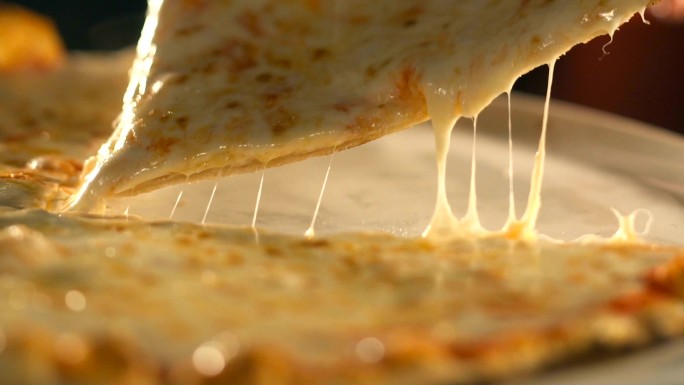 拿着一片披萨，融化的奶酪滴着。