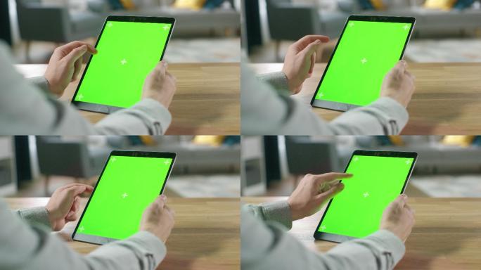 这名男子在使用绿色屏幕平板电脑