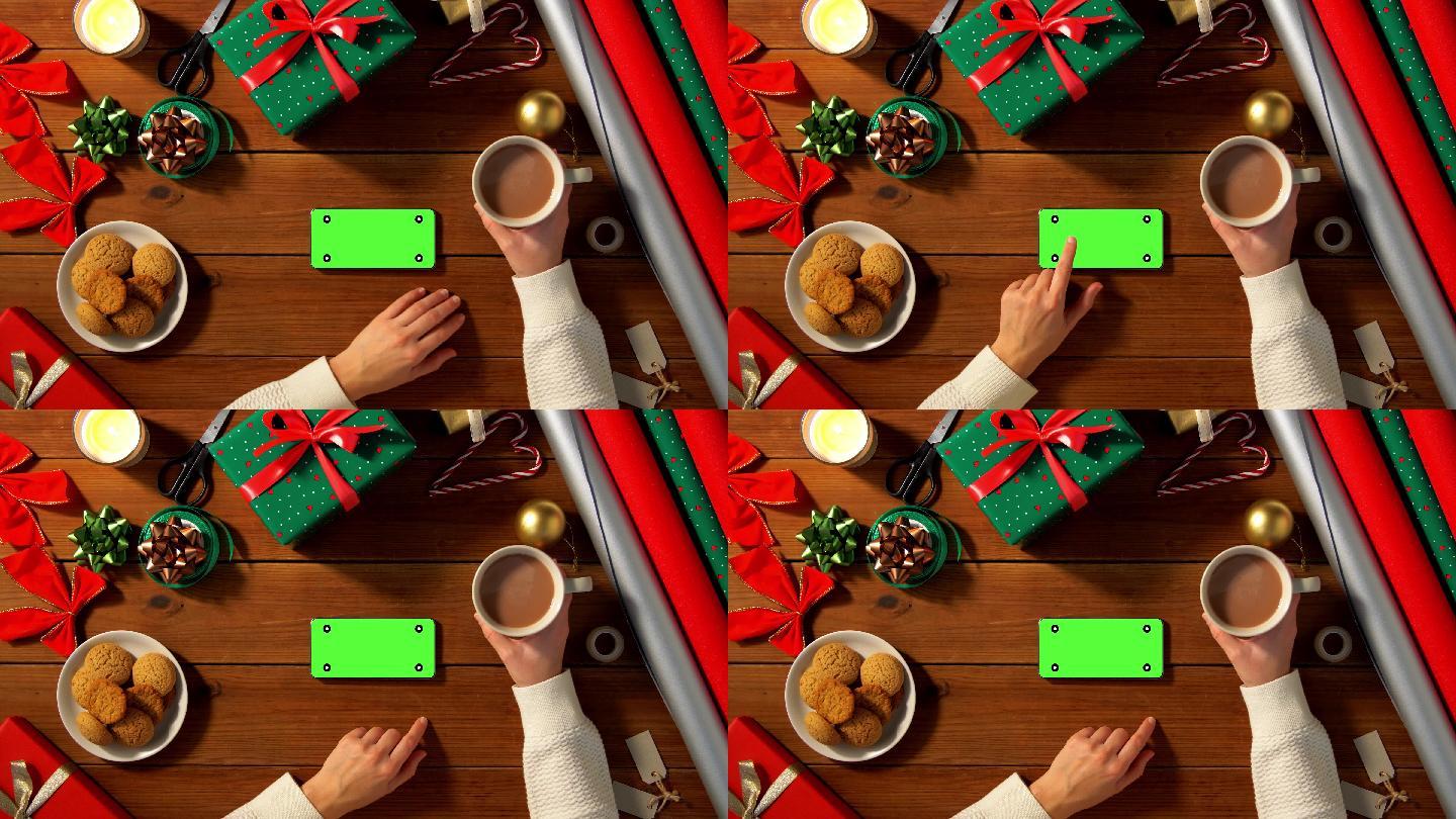 圣诞节使用绿屏智能手机和喝咖啡的女人