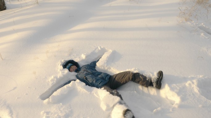 少年躺在雪地上。雪景雪原打雪仗