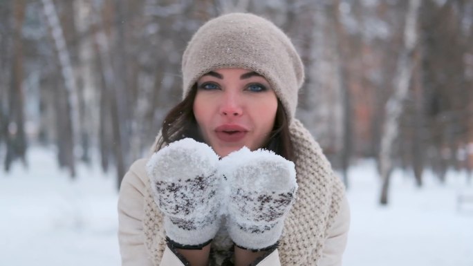 冬日森林里年轻女子吹着手上的雪