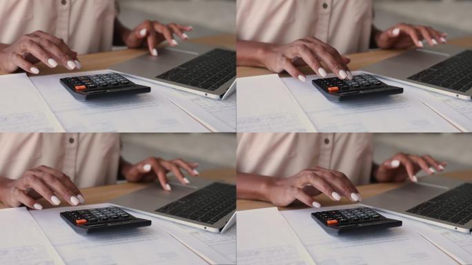 妇女使用计算器和笔记本电脑工作