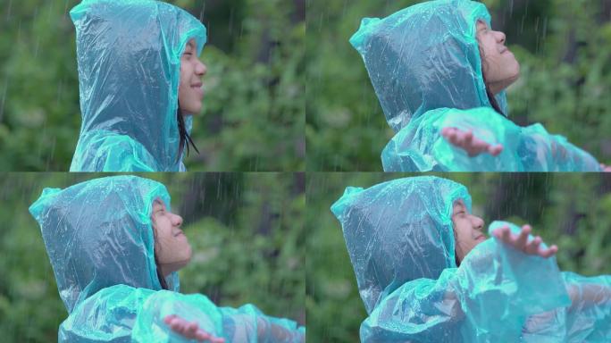 穿着蓝色雨衣享受雨水的女孩。