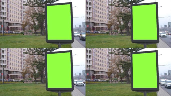 绿色屏幕广告牌位于绿色草坪和大型建筑旁边