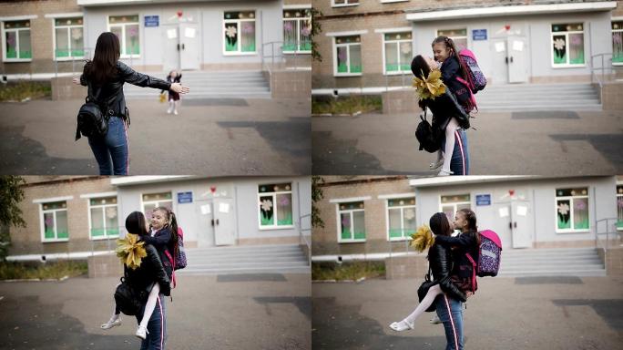 小女孩从学校跑出来迎接他的妈妈并拥抱她。