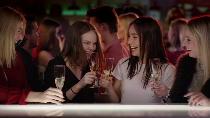 俱乐部酒吧里的四个女孩举起香槟酒杯