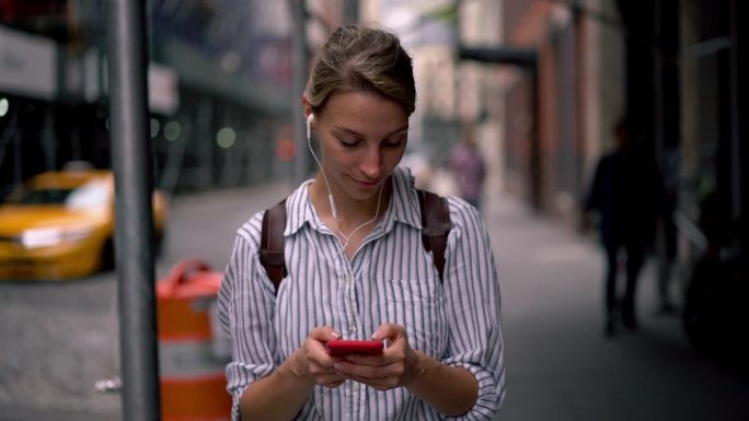 美丽的女性游客手持手机在在城市中搜索观光信息