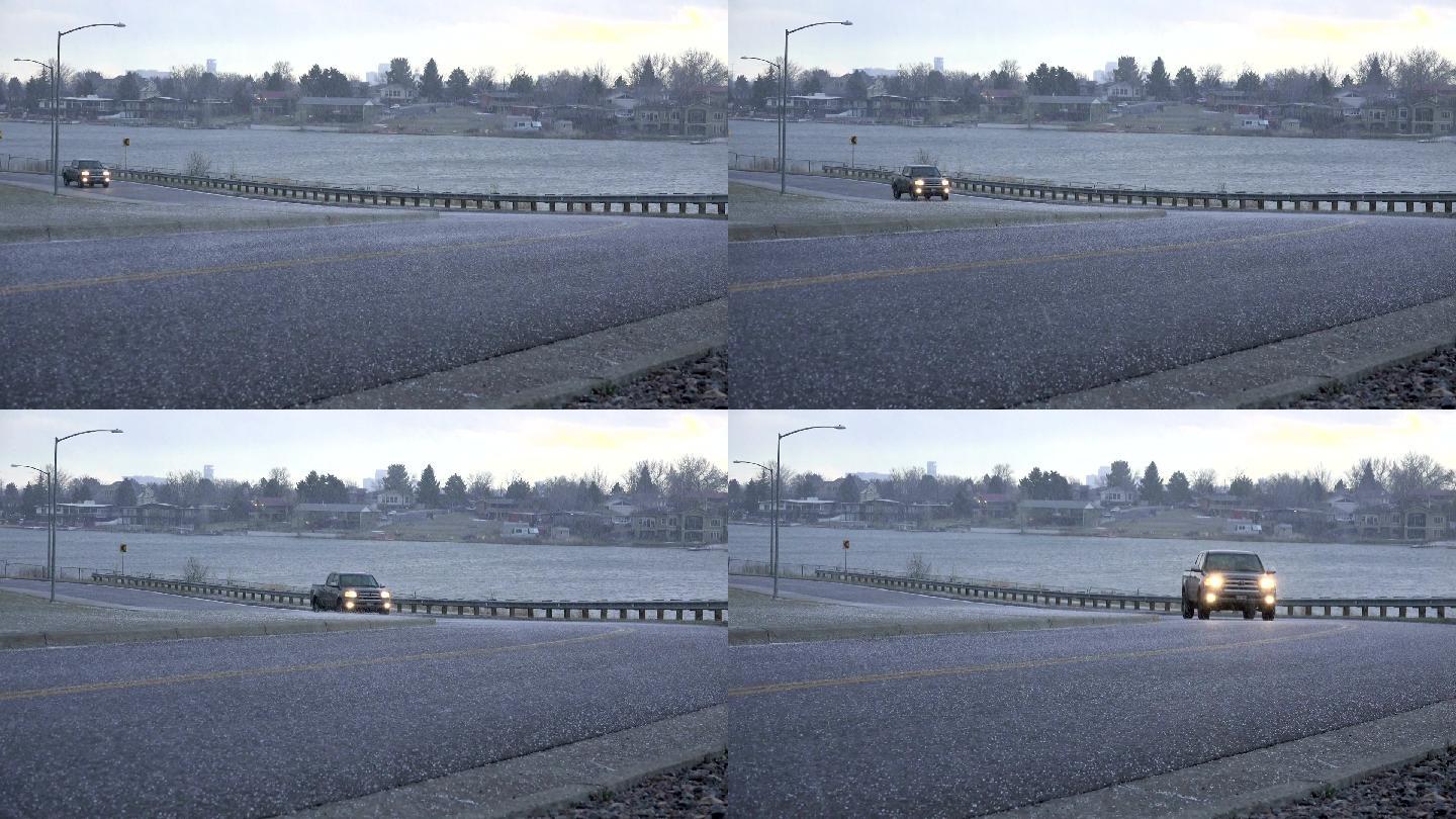 在冰雹风暴中，汽车沿着公路上坡行驶。