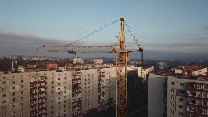 夕阳下建筑起重机无人机视图。城市建筑工地。