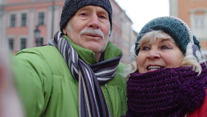 两位游客在冬季城市中心微笑着自拍
