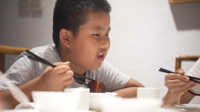 用筷子吃红烧肉的小男孩