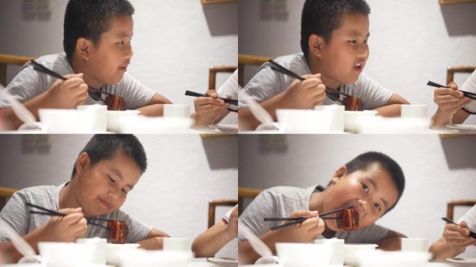 用筷子吃红烧肉的小男孩