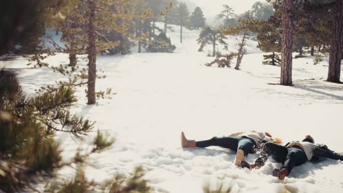 一对年轻夫妇躺在雪地里做雪天使