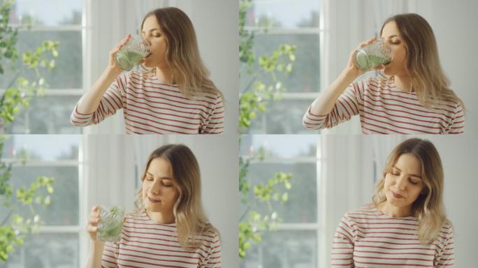 美丽的年轻女性用玻璃杯喝着健康的绿色饮料