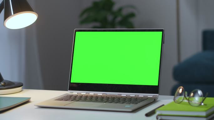在工作台上打开带有绿色屏幕的笔记本
