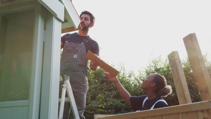 男木匠和女学徒在花园的室外凉亭上盖屋顶