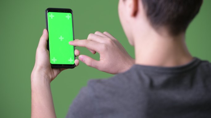绿色背景下年轻英俊的少年在使用手机