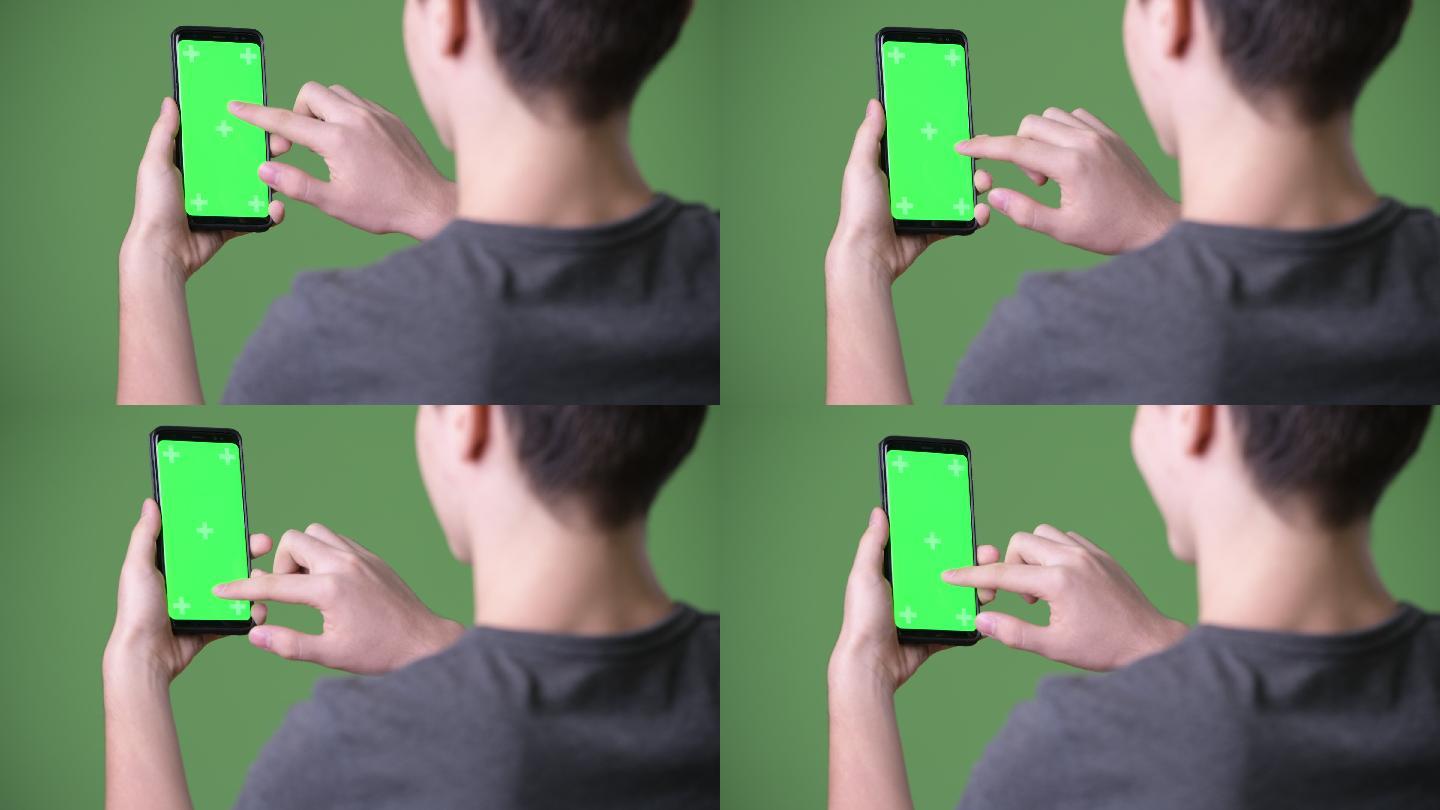 绿色背景下年轻英俊的少年在使用手机