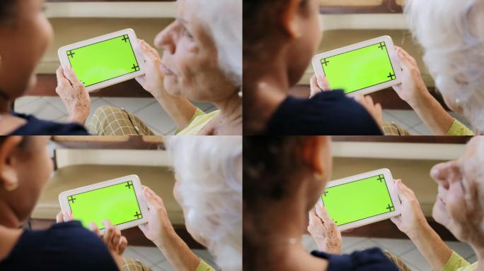 奶奶和孙女一起玩绿色屏幕平板电脑。