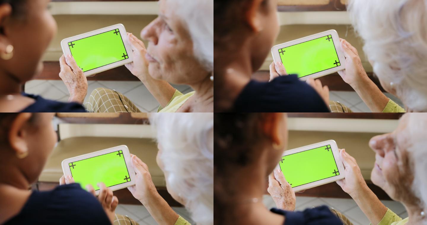 奶奶和孙女一起玩绿色屏幕平板电脑。