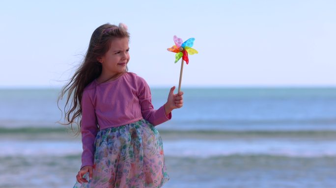 女孩在海滩上玩旋转的彩色风车