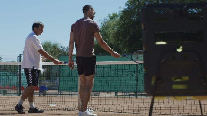 网球教练在球场上与男子一起练习