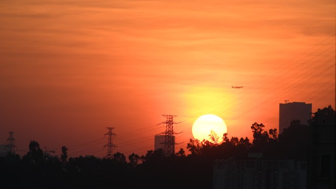 民航大飞机夕阳时分飞过大圆落日上方