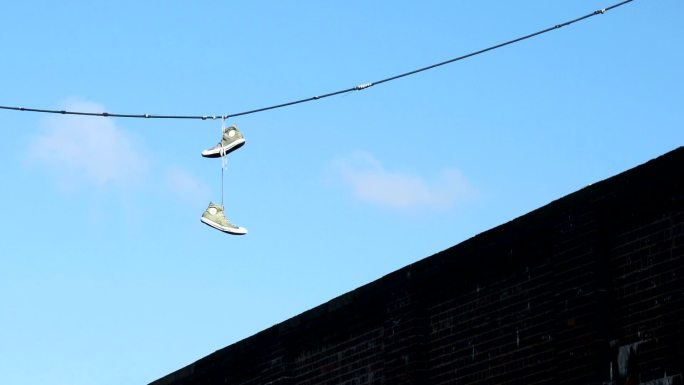 一双运动鞋悬挂在街道电缆上。