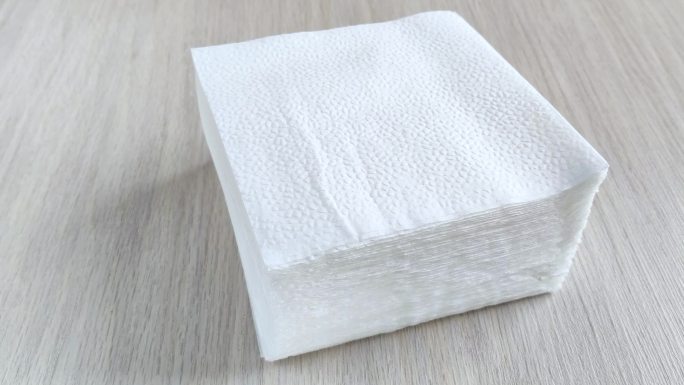木桌上一堆白色方形餐巾