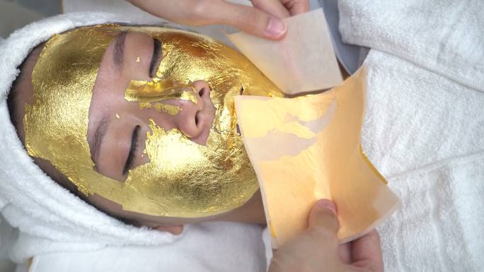 在美容诊所接受黄金面部护理的年轻女子。