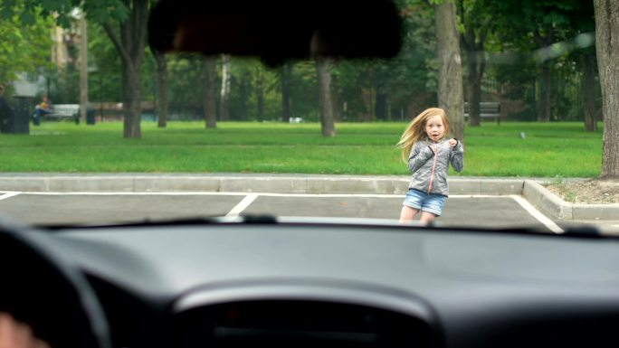 小女孩跑进室外停车场，司机及时刹车