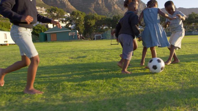 在草地上踢足球的小孩子