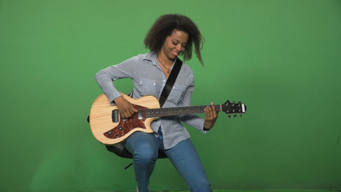 绿色背景前弹吉他的女人