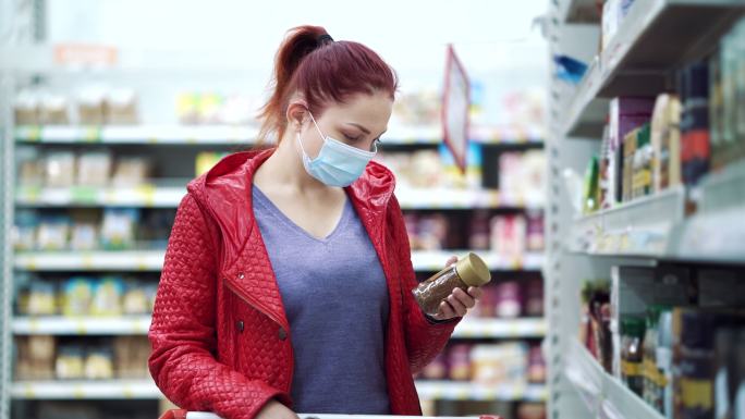 戴医用口罩的女人在商店里买速溶咖啡