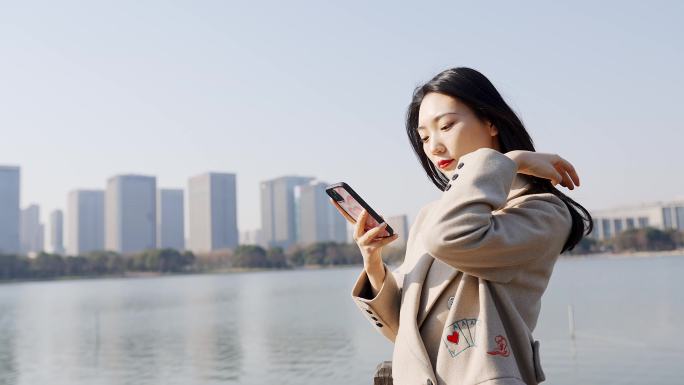 年轻都市女性无锡尚贤湖边拨弄头发玩手机
