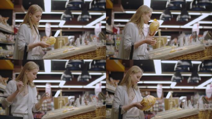 年轻女子选择和阅读市场上面包的标签。
