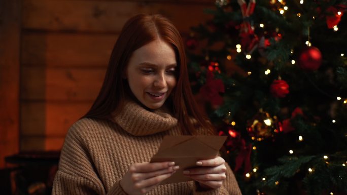 一位微笑的年轻女子正在阅读圣诞卡