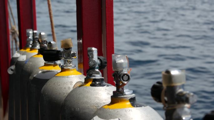 一排氧气罐和潜水设备放置在船上。