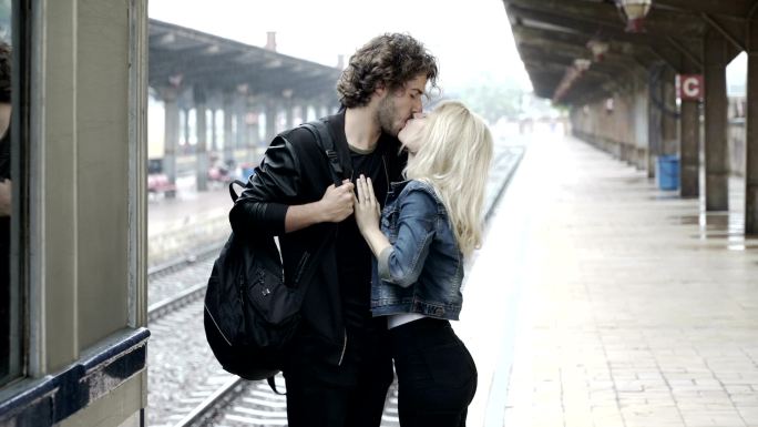 一对悲伤的年轻夫妇在火车站月台上说再见