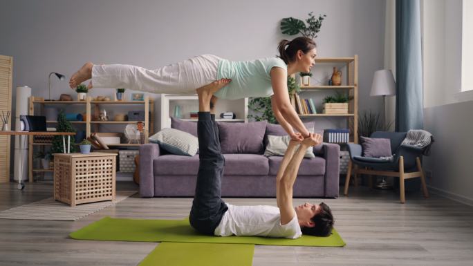 漂亮女孩和男朋友在家练习平衡瑜伽