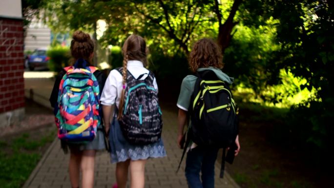 三名学生在城市街道上走路上学。