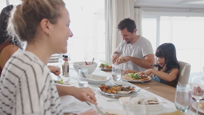 一家人围坐在家里的餐桌旁一起吃饭