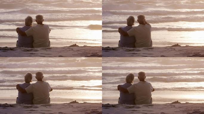 在海滩上观看日落的老年夫妇的后视图