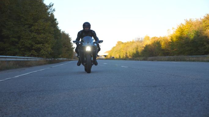 戴头盔的年轻人在高速公路上快速骑着摩托车
