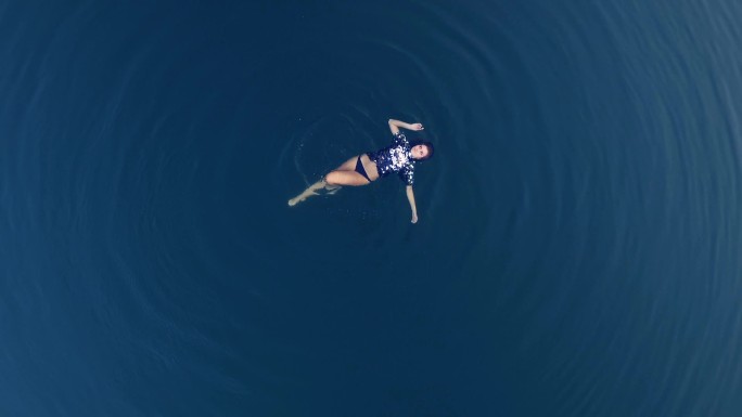 女孩在令人惊叹的蓝色水域中漂浮
