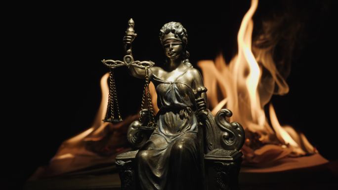 燃烧着的书的火焰背景下的正义女神雕像